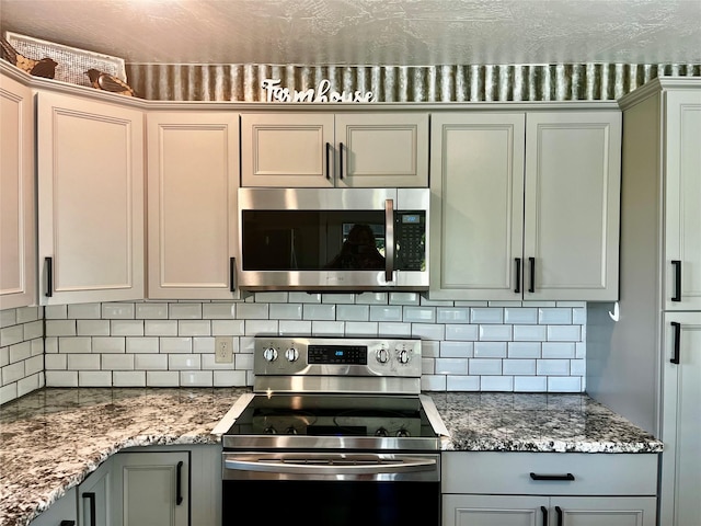 kitchen with appliances with stainless steel finishes, gray cabinets, and decorative backsplash