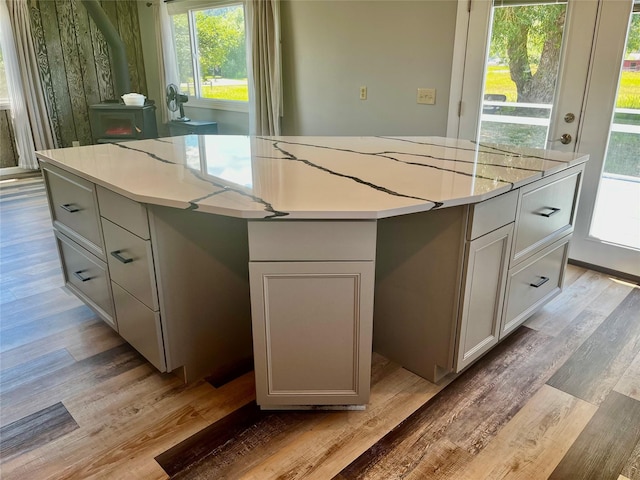 kitchen with a kitchen island, light wood-type flooring, and a wood stove