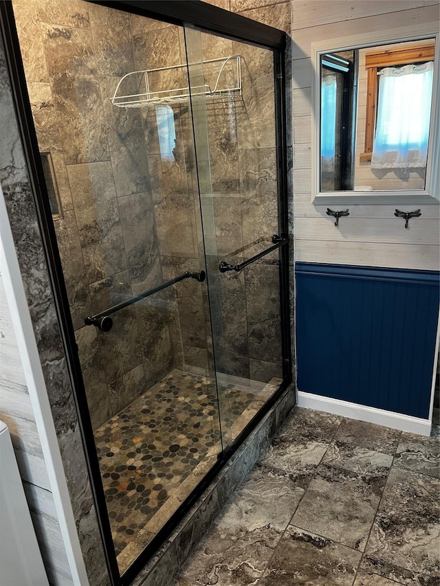 full bath featuring a shower stall and wood walls