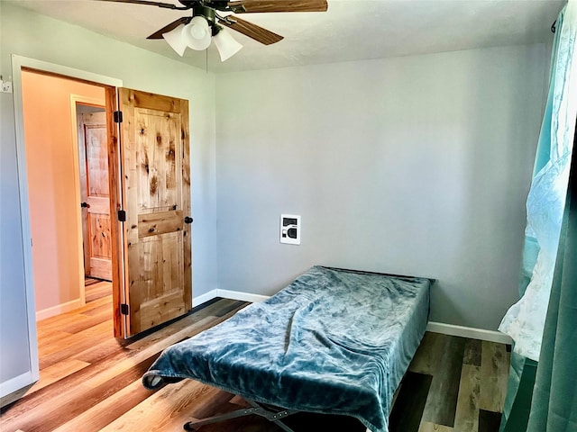 bedroom featuring baseboards, wood finished floors, and ceiling fan
