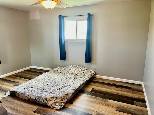 bedroom with baseboards, wood finished floors, and a ceiling fan