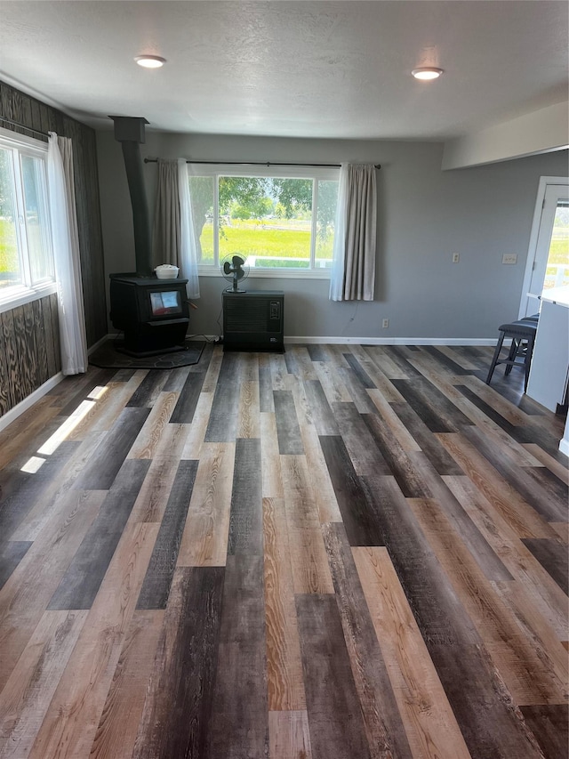 living room featuring a wood stove, healthy amount of natural light, wood finished floors, and baseboards