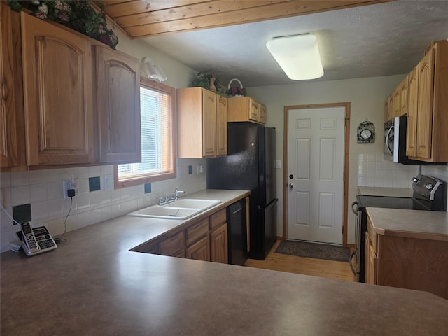 kitchen featuring black appliances, a sink, decorative backsplash, and light wood-style floors
