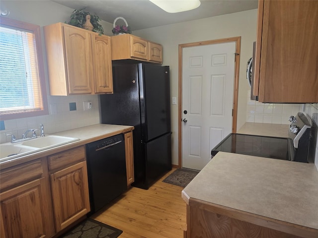 kitchen with black appliances, a sink, light wood-type flooring, tasteful backsplash, and light countertops