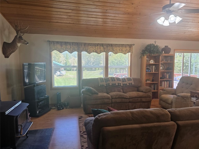 living area with wood ceiling, a ceiling fan, wood finished floors, and a wood stove