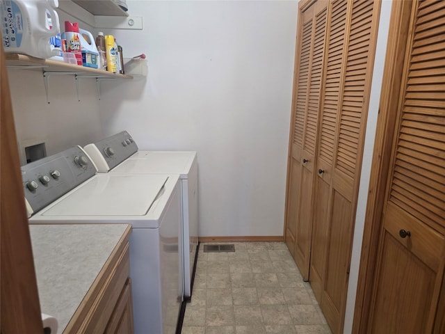 laundry area with washer and clothes dryer, baseboards, and stone finish floors