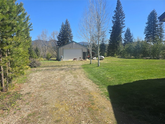 view of grassy yard with a garage, an outdoor structure, and a mountain view