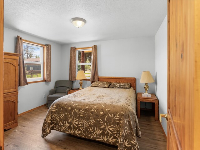 bedroom with wood finished floors, baseboards, and a textured ceiling