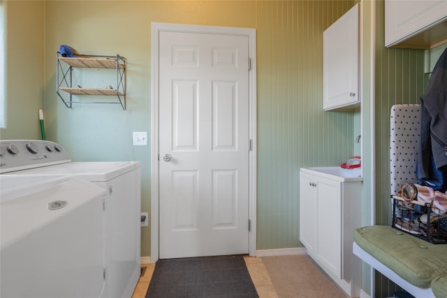washroom featuring washer and clothes dryer, cabinet space, and baseboards