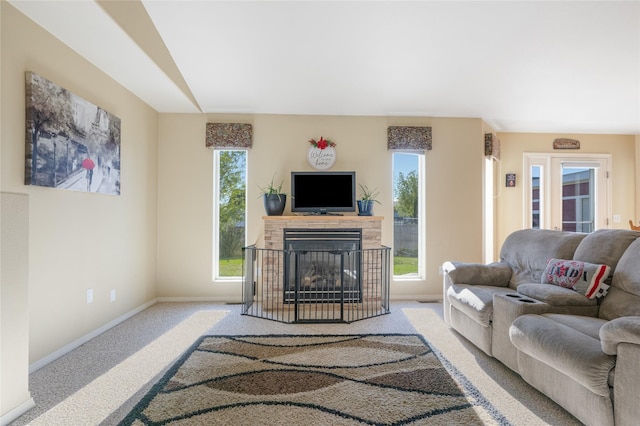 living room with baseboards, carpet flooring, and a stone fireplace