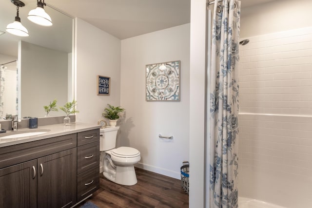bathroom with wood finished floors, toilet, a shower with curtain, baseboards, and vanity