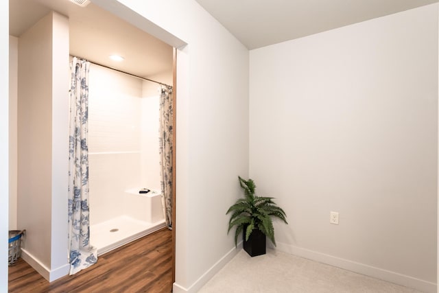 full bath featuring curtained shower, baseboards, and wood finished floors