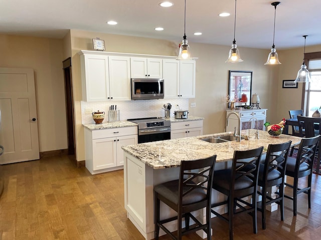 4195 Fox Hollow Dr, Helena, MT 59602 - kitchen with stainless steel appliances, a sink, tasteful backsplash, white cabinets, and a center island with sink