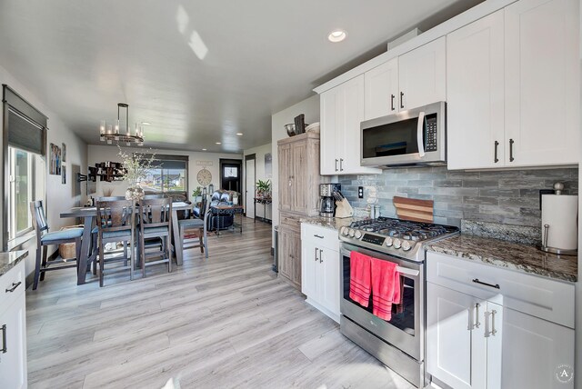 kitchen with appliances with stainless steel finishes, a chandelier, backsplash, light wood finished floors, and recessed lighting