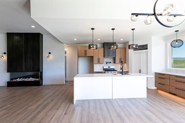 2736 Paniolo Pl, Missoula, MT 59808 - kitchen with stainless steel range with gas stovetop, a sink, light countertops, light wood finished floors, and baseboards