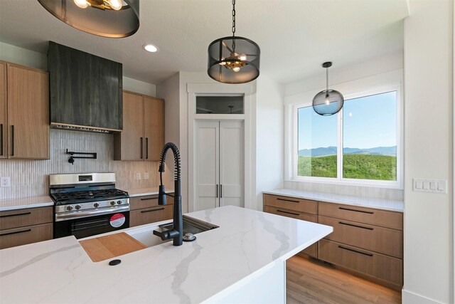 2736 Paniolo Pl, Missoula, MT 59808 - kitchen featuring gas range, tasteful backsplash, decorative light fixtures, light wood-style floors, and light stone countertops