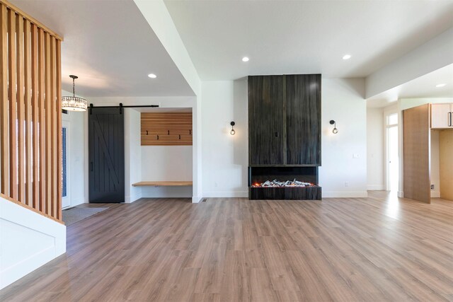 2736 Paniolo Pl, Missoula, MT 59808 - unfurnished living room featuring a barn door, light wood finished floors, baseboards, and recessed lighting