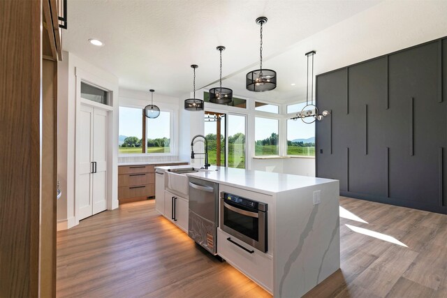 2736 Paniolo Pl, Missoula, MT 59808 - kitchen with modern cabinets, light wood finished floors, appliances with stainless steel finishes, a sink, and an island with sink