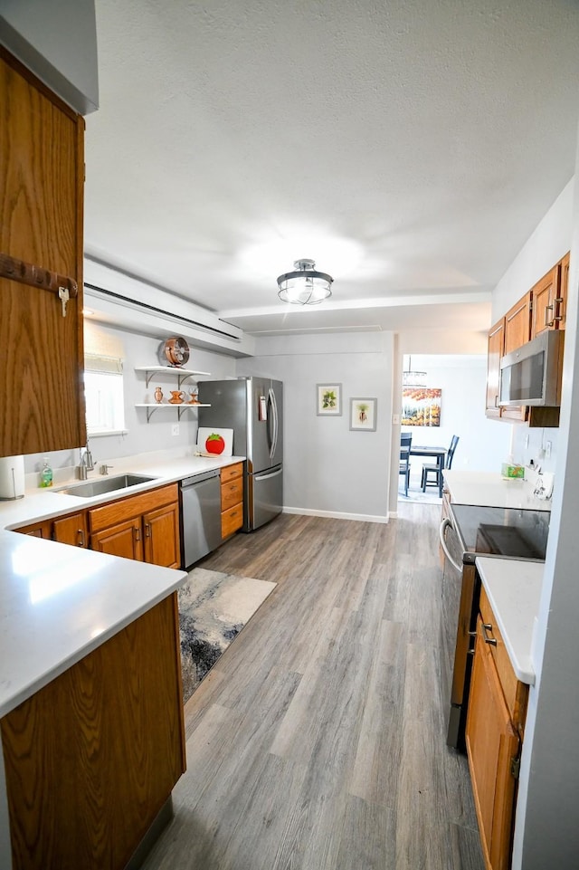 1536 Meadowlark Dr Unit 10B, Great Falls, MT 59404 - kitchen with appliances with stainless steel finishes, brown cabinets, wood finished floors, light countertops, and open shelves