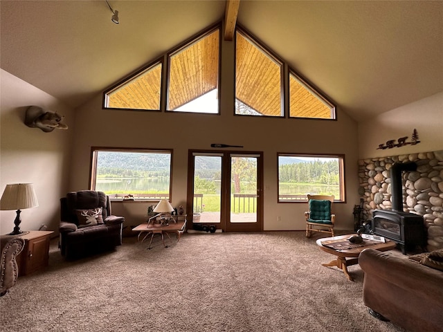 living room featuring a wood stove, carpet flooring, high vaulted ceiling, healthy amount of natural light, and beamed ceiling