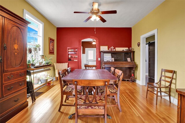 500 34th St NW, Great Falls, MT 59404 - dining area featuring arched walkways, light wood-style floors, a ceiling fan, and an accent wall