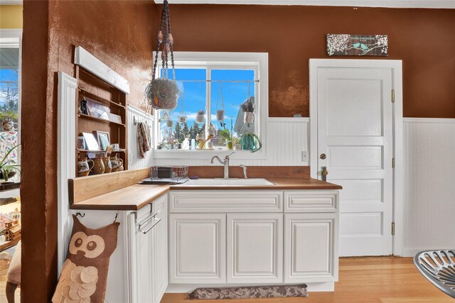 500 34th St NW, Great Falls, MT 59404 - kitchen featuring a sink, light wood-style flooring, wainscoting, white cabinets, and butcher block countertops
