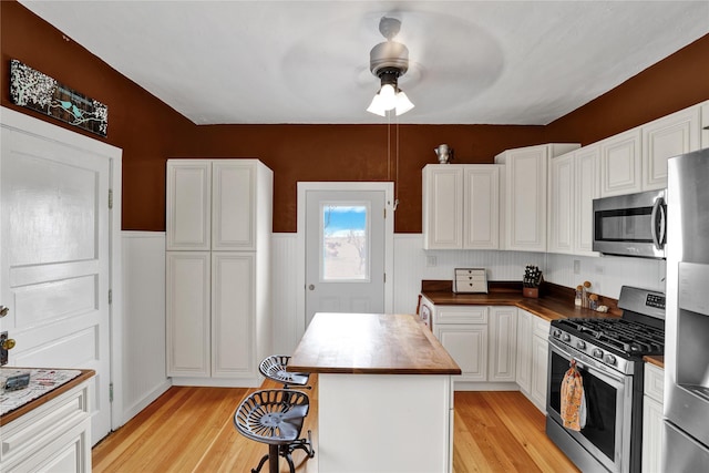 500 34th St NW, Great Falls, MT 59404 - kitchen featuring appliances with stainless steel finishes, wood counters, light wood-style flooring, ceiling fan, and wainscoting