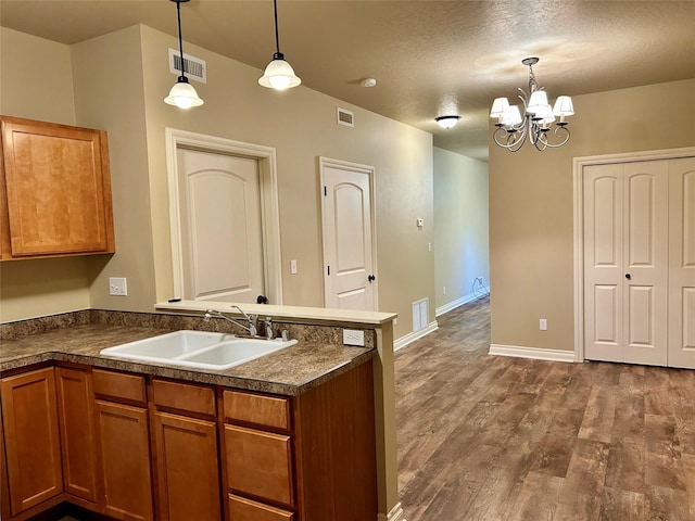 2905 Oshaughnesy St Unit 104, Missoula, MT 59808 - kitchen with a sink, brown cabinets, a peninsula, dark countertops, and a textured ceiling