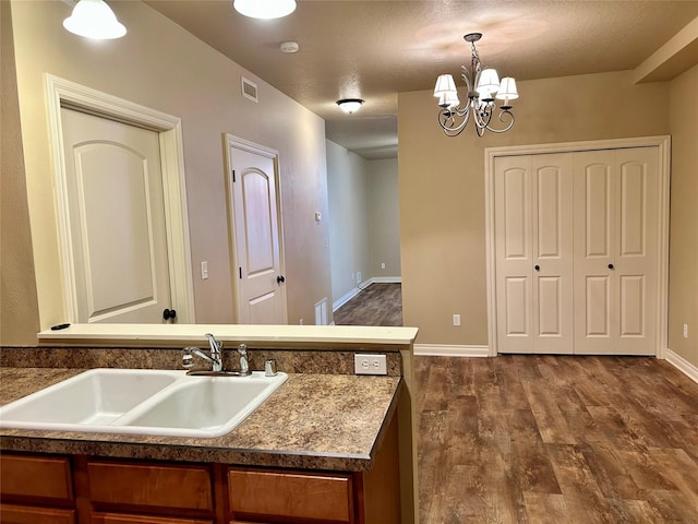2905 Oshaughnesy St Unit 104, Missoula, MT 59808 - kitchen with a sink, dark wood-type flooring, a chandelier, hanging light fixtures, and brown cabinetry