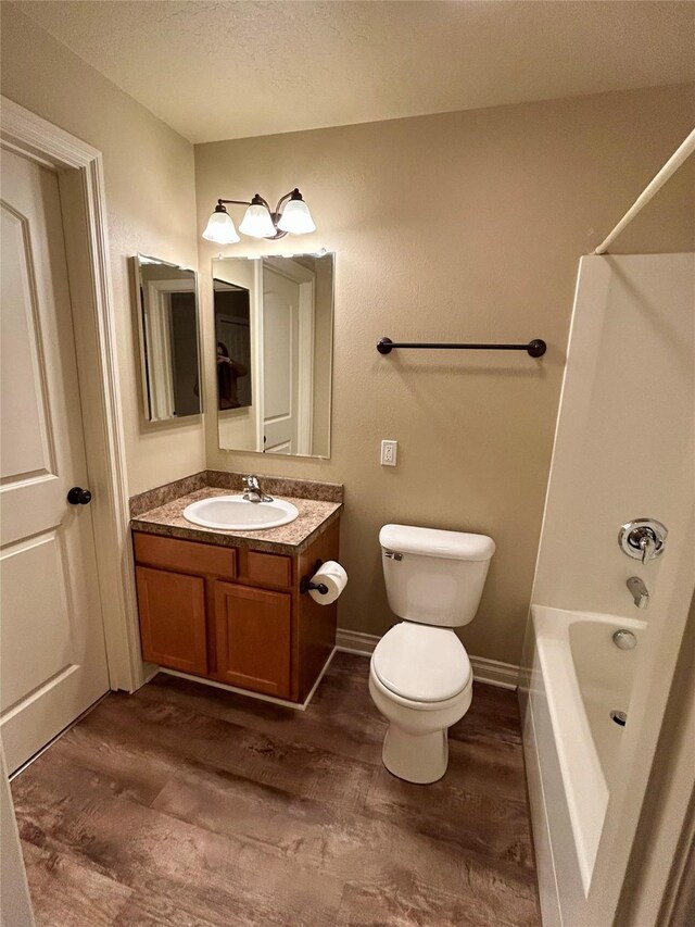 2905 Oshaughnesy St Unit 104, Missoula, MT 59808 - full bathroom with vanity, washtub / shower combination, a textured ceiling, wood finished floors, and toilet