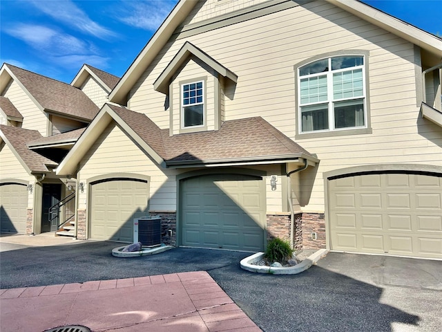 2905 Oshaughnesy St Unit 104, Missoula, MT 59808 - view of front facade featuring a garage, central AC, driveway, and stone siding