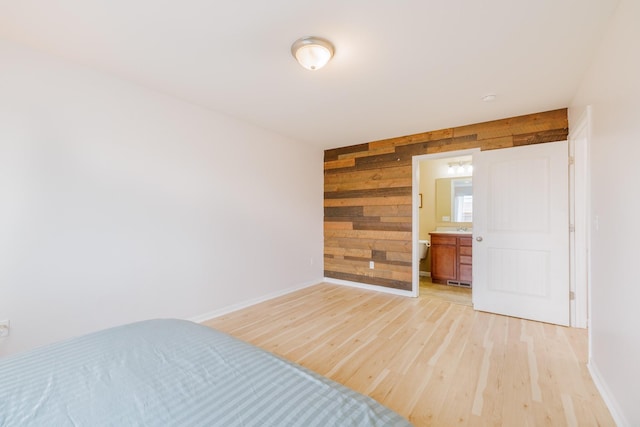 unfurnished bedroom featuring light wood-type flooring, wooden walls, and baseboards