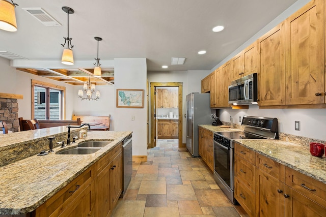 kitchen featuring stainless steel appliances, a sink, stone tile floors, recessed lighting, and pendant lighting