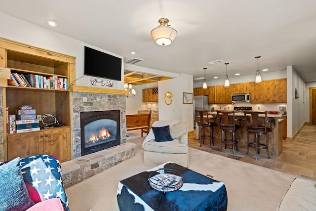 living area featuring a stone fireplace and recessed lighting