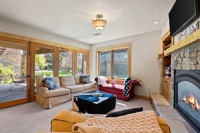 living room featuring carpet flooring, a stone fireplace, and baseboards
