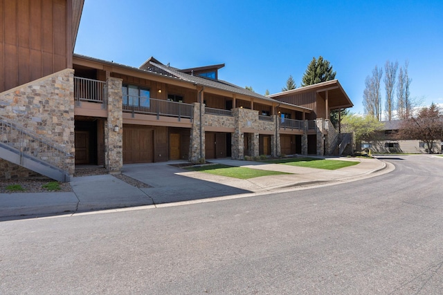 view of building exterior with a garage, concrete driveway, and stairs