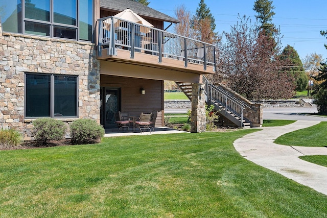 back of house with stone siding, a lawn, stairway, and a patio