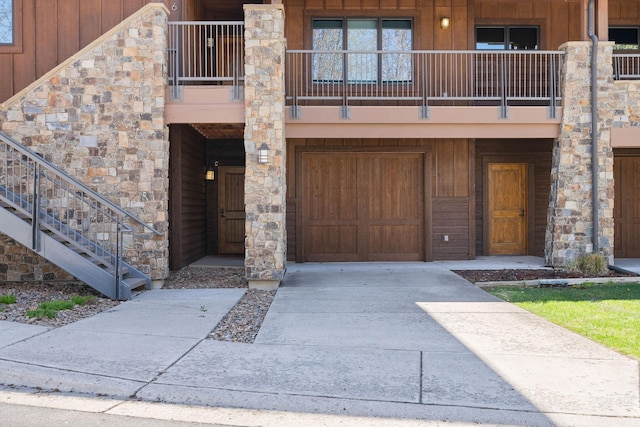 doorway to property with concrete driveway, a balcony, and a garage