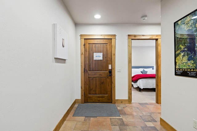 entryway with baseboards, stone finish flooring, and recessed lighting