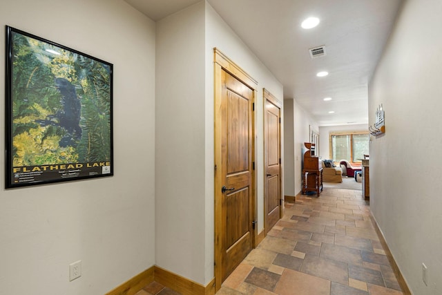 hallway with baseboards, recessed lighting, and stone tile flooring