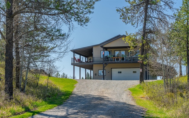 5550 Farm To Market Rd, Whitefish, MT 59937 - view of front of house featuring a garage, a balcony, and gravel driveway