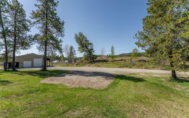 5550 Farm To Market Rd, Whitefish, MT 59937 - view of green lawn featuring a garage, dirt driveway, and an outdoor structure