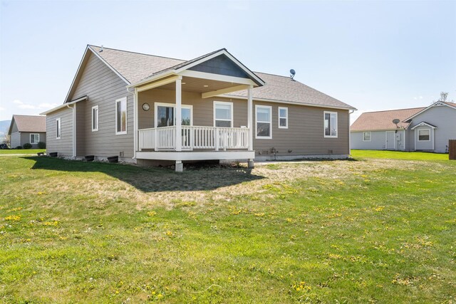 rear view of property with a yard, a deck, and a shingled roof