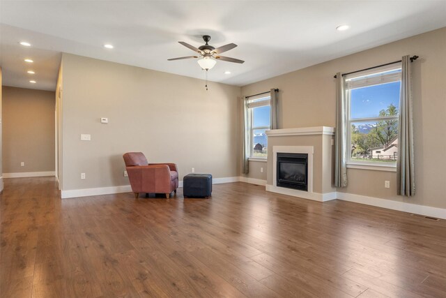 unfurnished living room featuring ceiling fan, wood finished floors, recessed lighting, a glass covered fireplace, and baseboards