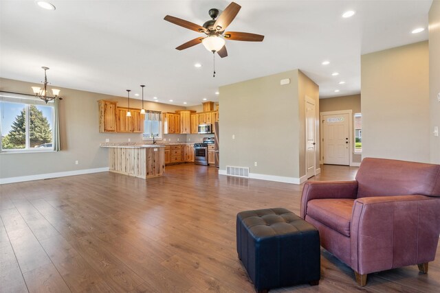 living area featuring plenty of natural light, ceiling fan, baseboards, a chandelier, and recessed lighting