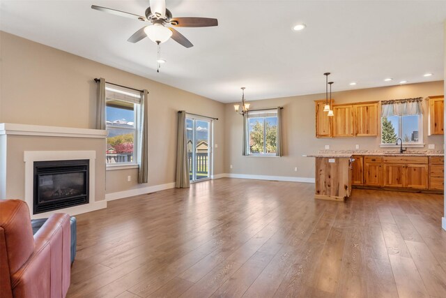 unfurnished living room with a sink, baseboards, recessed lighting, a ceiling fan, and light wood-style flooring