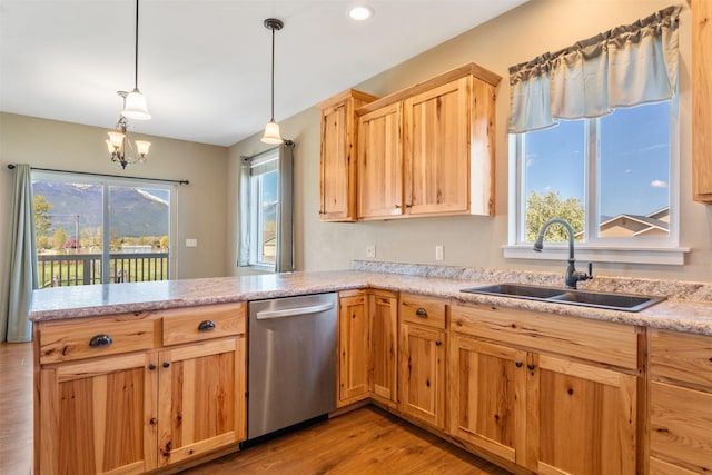 kitchen featuring dishwasher, a sink, light wood-style floors, a peninsula, and light countertops