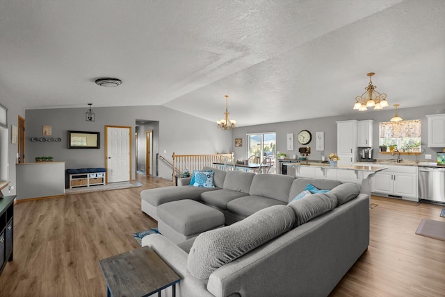 556 Fescue Slope Rd, Florence, MT 59833 - living area with a chandelier, light wood-style flooring, lofted ceiling, and a textured ceiling