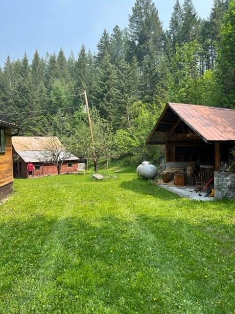 view of grassy yard with a view of trees