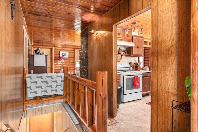 kitchen with white gas stove, wood ceiling, under cabinet range hood, and log walls